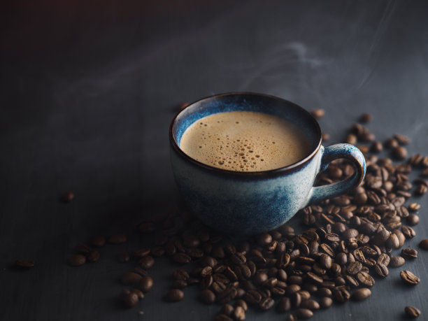 黑色桌子上的一杯咖啡和烤好的咖啡豆图片下载
