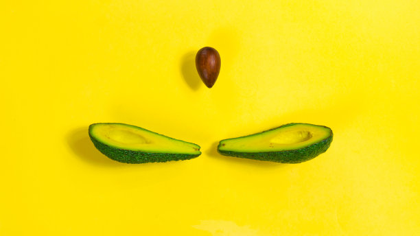 在一张黄色的特写照片中，两片成熟的鳄梨中间有一个核。图片下载