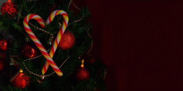 圣诞树上的两根糖果棒的全景图，上面有红色的圣诞球和金色的珠子图片下载