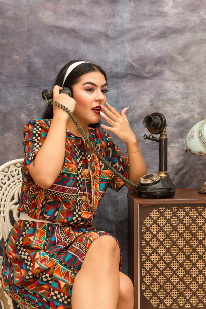 惊讶的拉丁女人的肖像在别针风格，而谈论一个旧的电话。复古复古风格场景图片下载