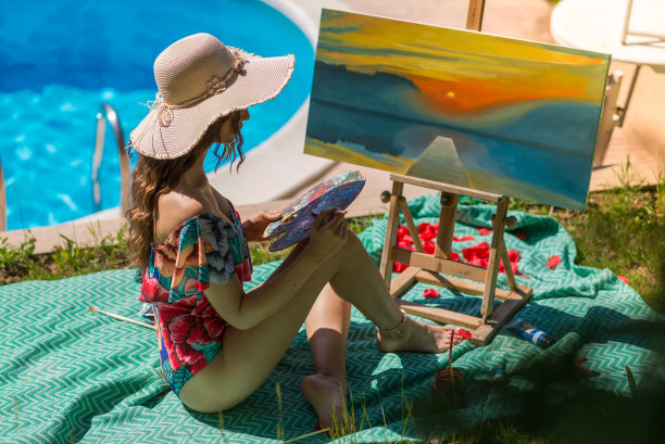美丽的女艺术家在大自然的水池边绘画，库存照片图片下载