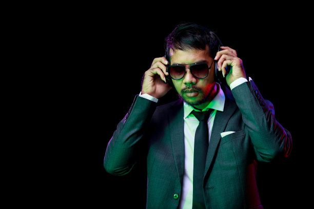 戴眼镜的亚洲帅哥喜欢戴着黑色耳机听音乐图片下载