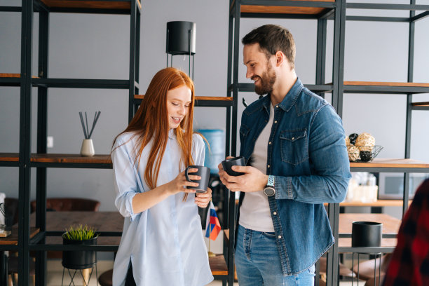 两位年轻成功的创业同事在共同工作的空间享受愉快的谈话在咖啡休息。图片下载
