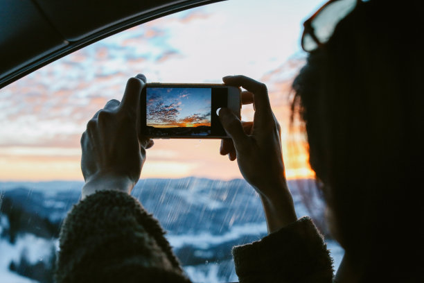 用智能手机拍摄日落的女人图片下载