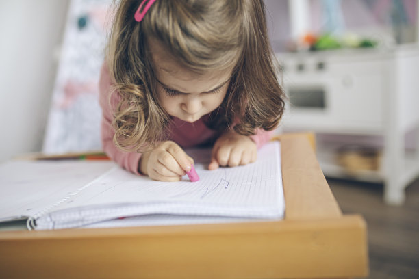小女孩在她粉红色的房间里用蜡笔画画图片下载