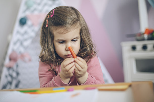 小女孩在她粉红色的房间里用蜡笔画画图片下载