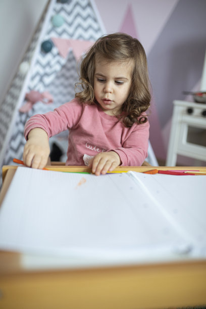 小女孩在她粉红色的房间里用蜡笔画画图片下载