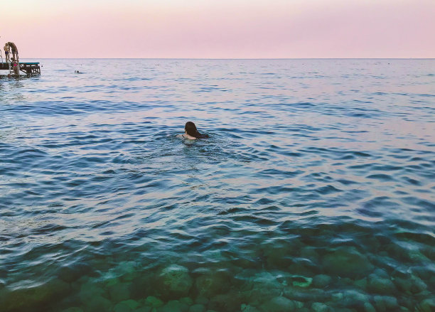 一个黑头发的女孩在海里游泳。美人鱼在海里游泳。休息休假。克鲁斯。女孩游到浮标后面很远的地方图片下载