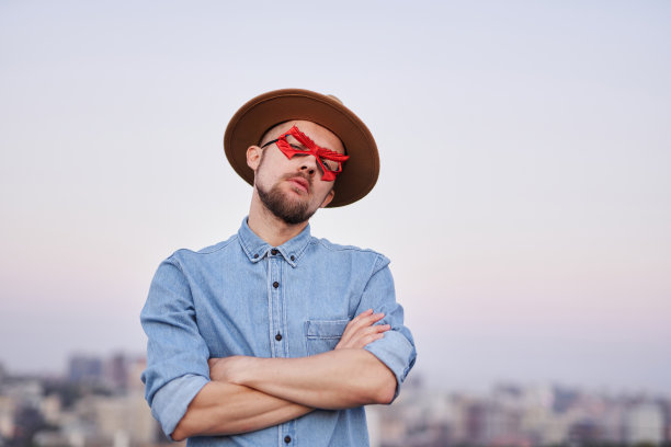 超级英雄，戴着红色眼罩和帽子，双臂交叉在户外图片下载