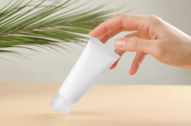 为身体护理的天然化妆品。用手触摸涂有保湿霜的化妆管。图片下载