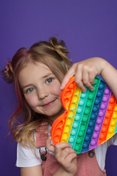 一个小女孩手里拿着一个流行的pop it玩具。图片下载