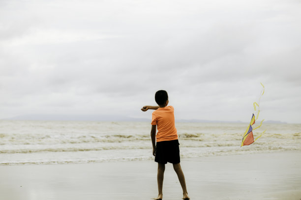 亚洲小孩拿着风筝在沙滩上奔跑图片下载