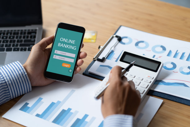 在办公室，男性手握智能手机和网上银行屏幕和信用卡。网上购物的概念。图片下载