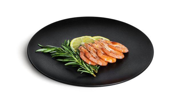 用柠檬和迷迭香在白色背景的黑色盘子上煮虾图片下载