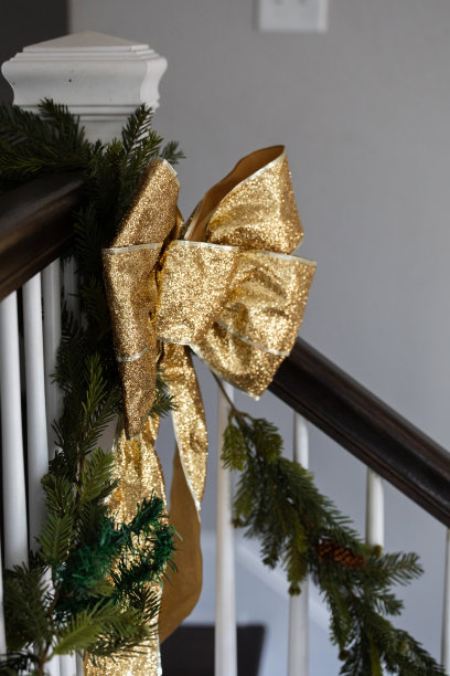 假日圣诞楼梯装饰绿色花环和金色闪光弓为节日的圣诞节或新年晚会庆祝图片下载