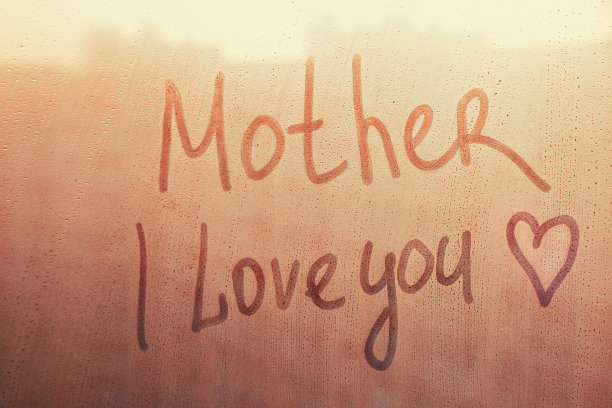 文字妈妈我爱你用心形的手指写在橘黄色夕阳湿窗上图片下载