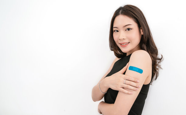 快乐的接种疫苗的妇女在注射新冠肺炎疫苗后，用石膏绷带包扎手臂，孤立的白色背景，微笑，复制空白空间。冠状病毒疫苗接种的广告。图片下载