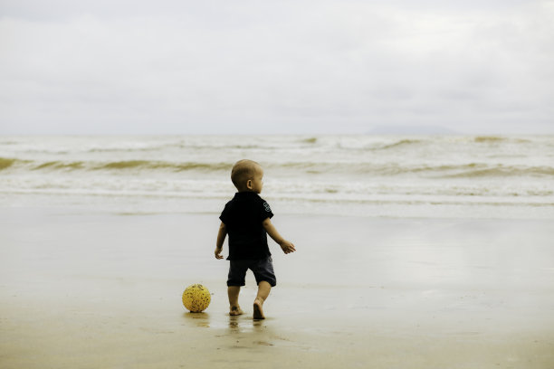 宝宝在沙滩上踢足球图片下载