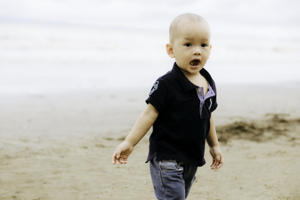 小男孩在海滩上散步，微笑着图片下载