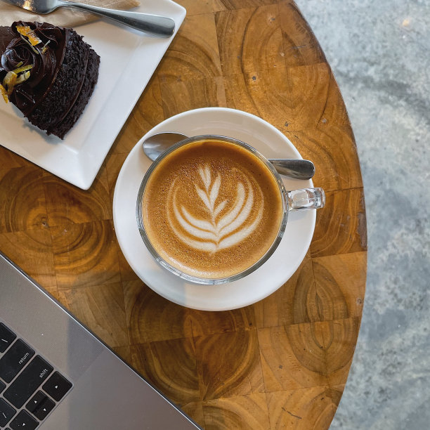 木咖啡屋桌上有笔记本电脑，一杯咖啡和一块蛋糕。图片下载