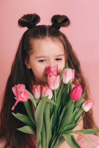 粉红色背景上的郁金香女孩的肖像。图片下载