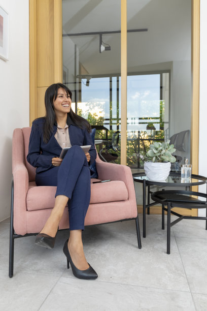 年轻的女高管一边坐在扶手椅上，一边用她的数码平板电脑工作图片下载