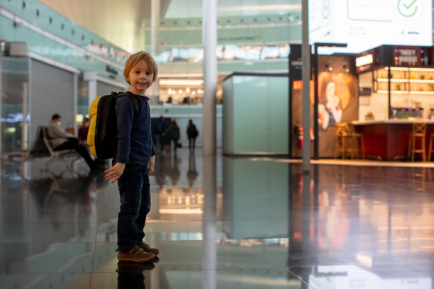 可爱的小男孩在机场登机口附近的中转大厅等待登机。积极的家庭生活方式与孩子乘飞机旅行图片下载