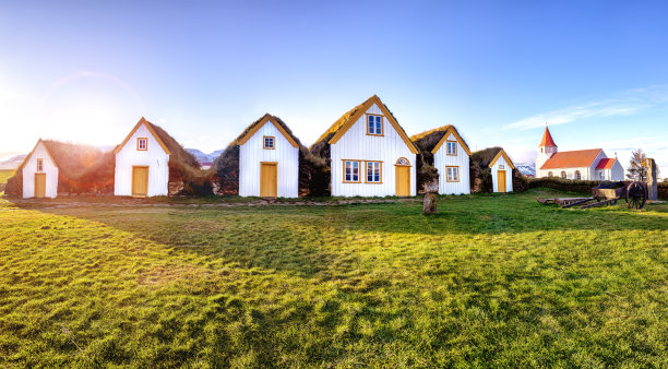 冰岛西北部格伦巴尔传统的草屋顶房屋，背景是红色屋顶的教堂。傍晚阳光下的全景。图片下载