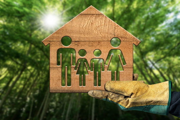 戴着工作手套的手在森林里拿着一座小木屋图片下载