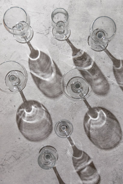 空的酒杯在灰色的背景上。阳光直射，审美静物图片下载