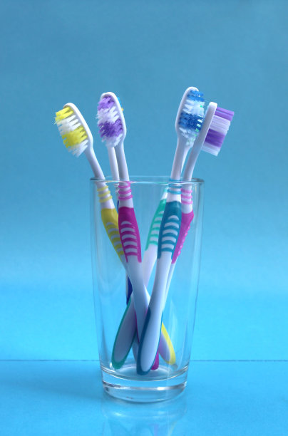 五支牙刷放在蓝色背景的玻璃烧杯里图片下载