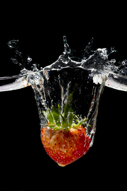 红色草莓水溅在黑色的背景上。图片下载