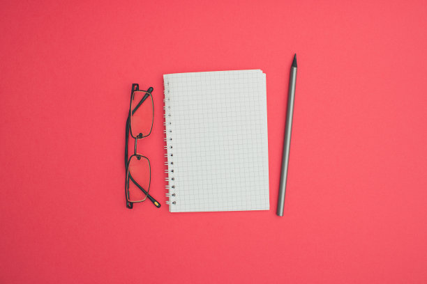 商务A6笔记本线材装订模拟空白模板设计思路。眼镜和灰色石墨铅笔模型在柔和的粉红色背景。复制消息布局的空间模板设计。图片下载