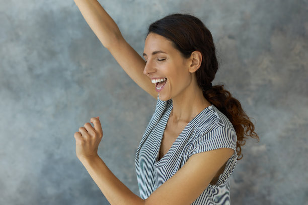 剪裁工作室拍摄的迷人可爱的快乐的女性听到好消息后兴奋地跳起来，举起手，闭上眼睛，笑。人类的情感和感觉。肢体语言图片下载