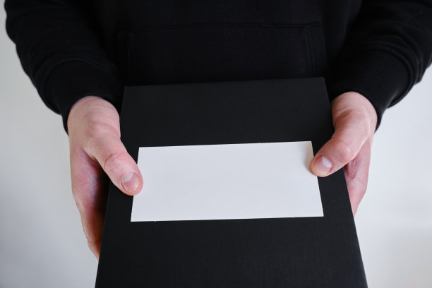 白色的空牌在一个男人的手中在黑色的背景上。放置文字和广告。名片图片下载