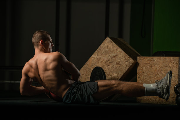 赤裸上身的职业运动员在做俄罗斯式的腹肌扭转训练。一个健康的男性运动员做室内训练的特写照片。图片下载