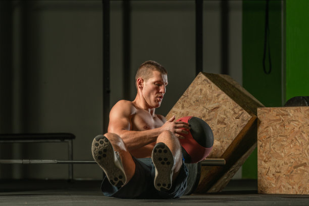 一个英俊的健美运动员坐着用实心球锻炼身体的特写照片图片下载