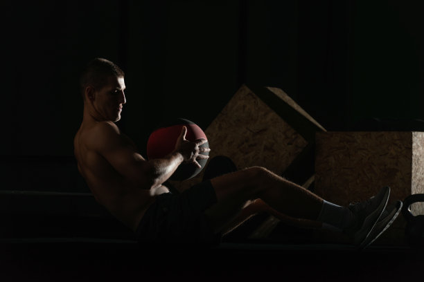 赤裸上身的职业运动员在做俄罗斯式的腹肌扭转训练。一个健康的男性运动员做室内训练的特写照片。图片下载