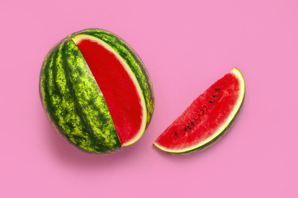 创意夏日美食概念。半块熟多汁的红色西瓜在亮粉色的背景上。平躺，顶视图，复制空间。鲜嫩多汁的夏季浆果图片下载