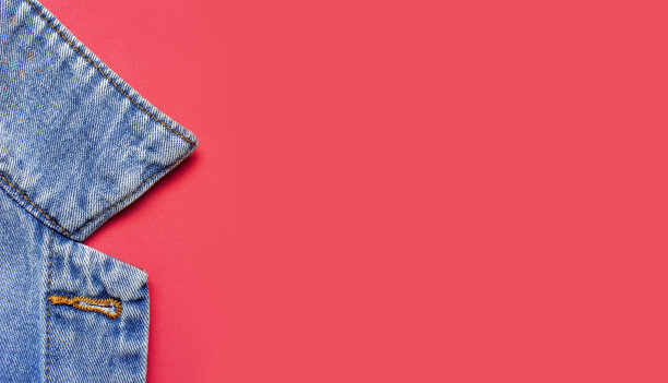 特写蓝色牛仔夹克在粉红色的背景顶视图平躺复制空间。牛仔布，时尚夹克，女装或男装潮流服装，时尚背景。牛仔质地图片下载