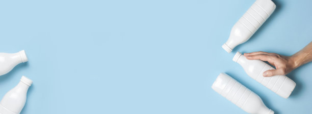 白色塑料瓶容器乳制品在男性手中蓝色背景俯视图平躺。塑料开菲尔酸奶奶瓶。包装模板模型。设计的布局图片下载