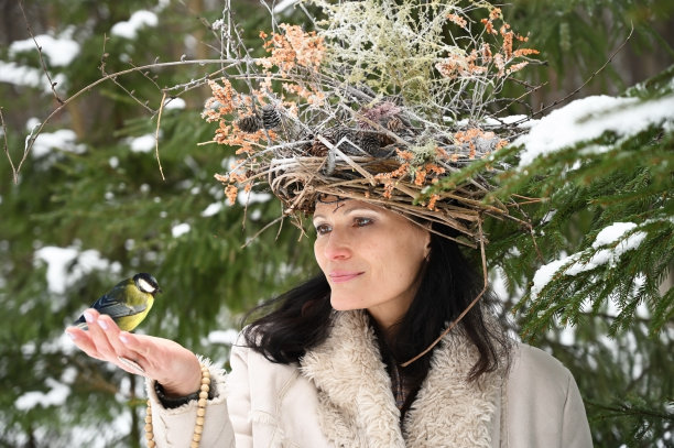 冬天的森林里，一个手拿山雀的美丽女人图片下载