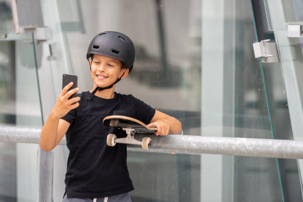 戴着头盔的黑发少女在混凝土建筑前的站台上玩滑板图片下载