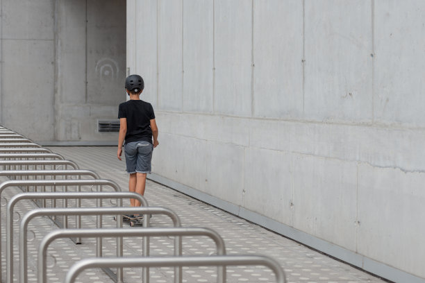戴着头盔的黑发少女在混凝土建筑前的站台上玩滑板图片下载