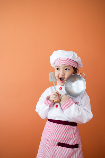 穿着厨师服的可爱亚洲女孩。为孩子学习烹饪的概念。图片下载
