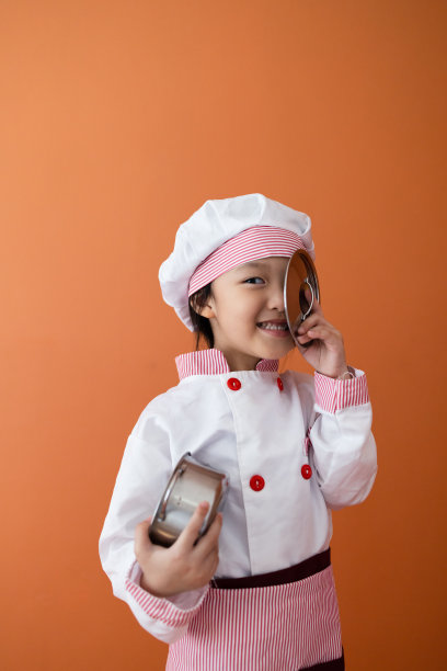 穿着厨师服的可爱亚洲女孩。为孩子学习烹饪的概念。图片下载