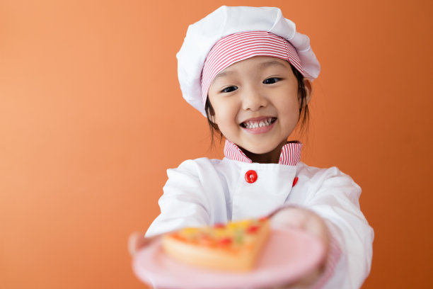 穿着厨师服的可爱亚洲女孩。为孩子学习烹饪的概念。图片下载