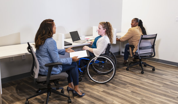 三个女商人在办公室工作，一个坐轮椅图片下载