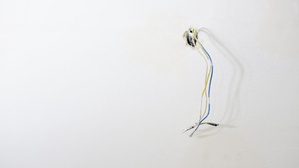 在一间正在装修的公寓里，彩色电缆从白色墙壁的波纹管中伸出。图片下载