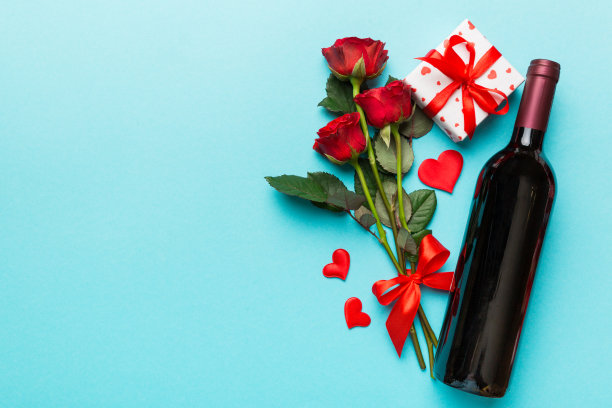 情人节搭配红酒、玫瑰和礼盒放在桌子上。俯视图，平躺。节日的概念图片下载